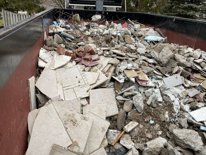 loaded dumpster filled with broken tiles and debris