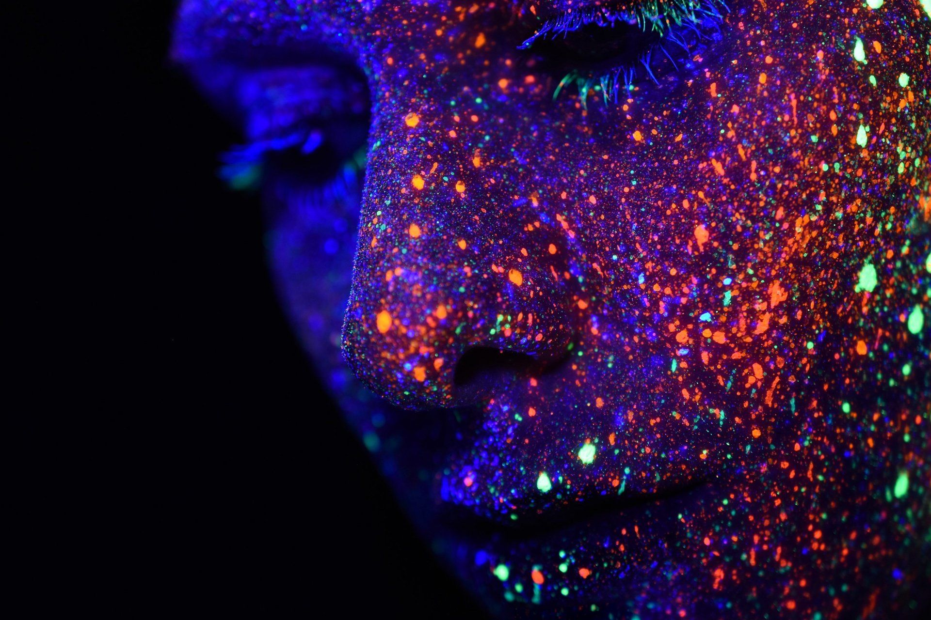A close up of a person 's face with glow in the dark paint on it.
