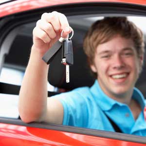 Young male driver holding car keys, celebrating passing his test