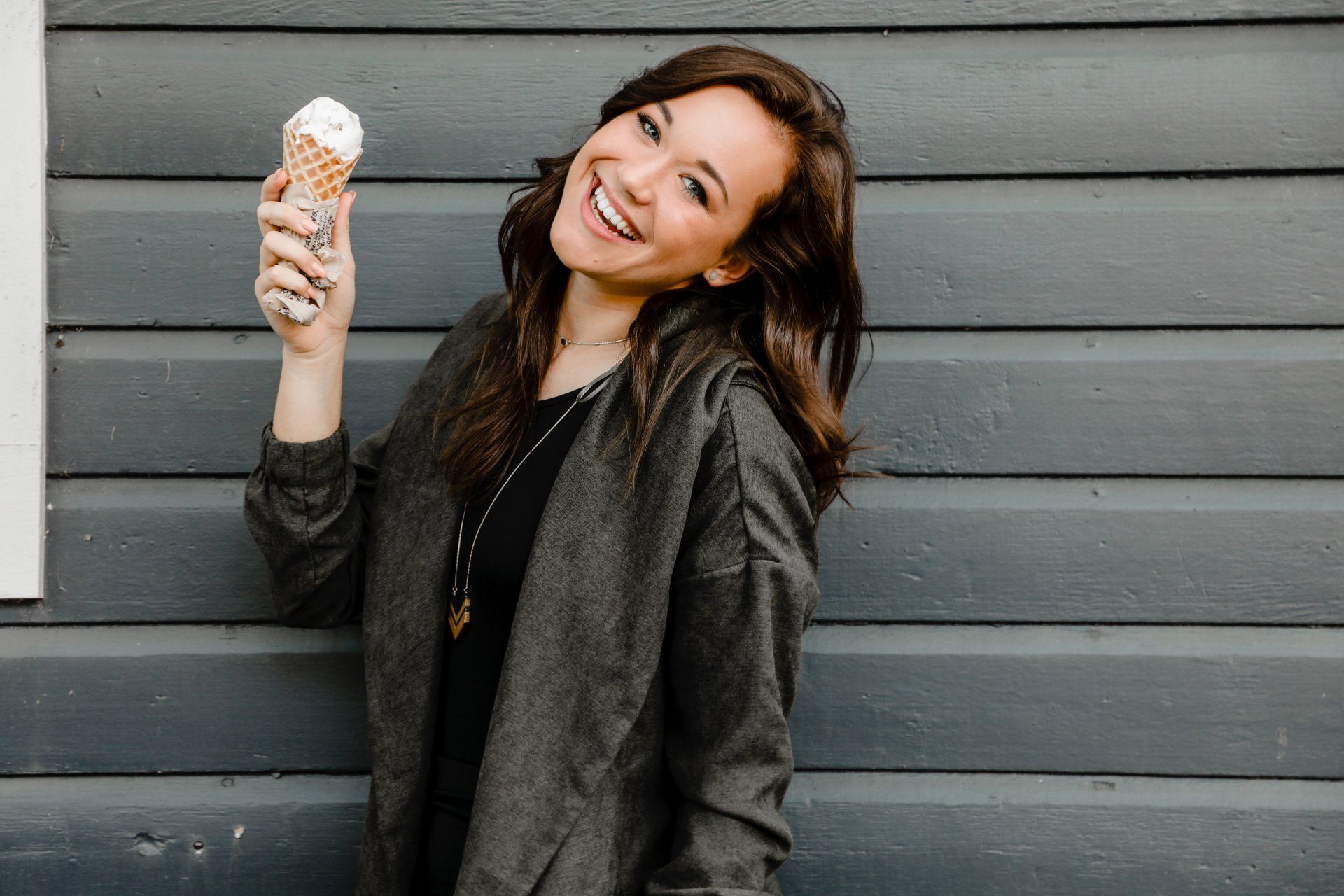 A woman is smiling while holding an ice cream cone