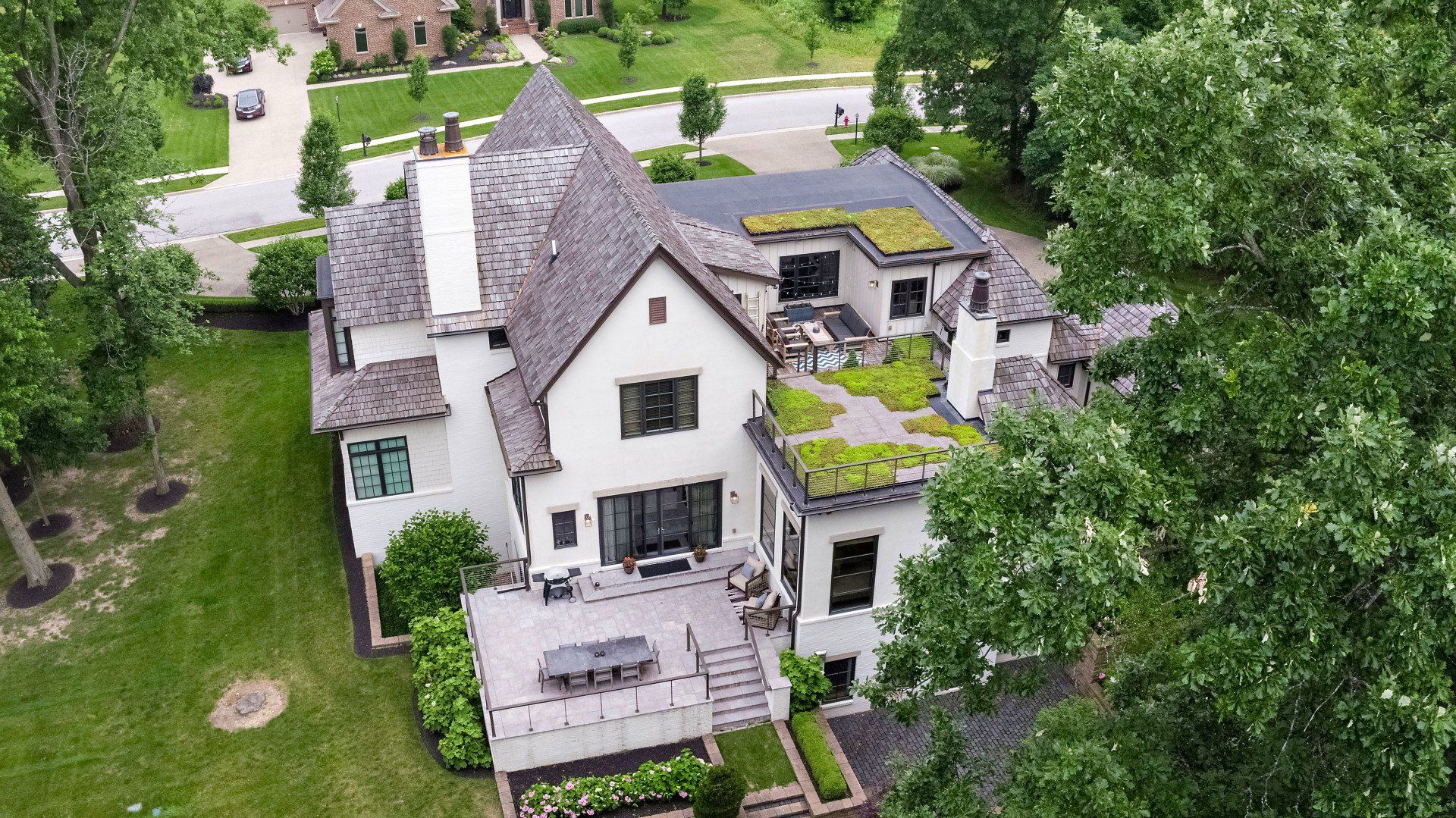 An aerial view of a large white house with a green roof