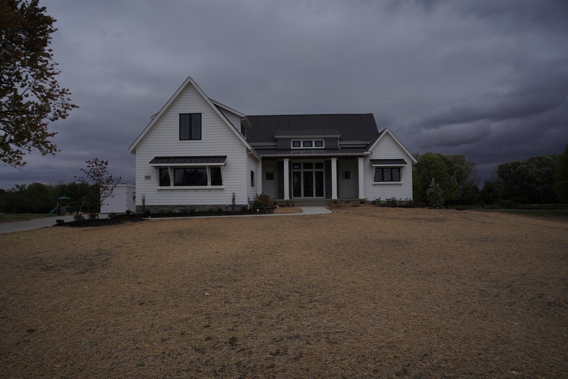 A white house sits in the middle of a gravel field