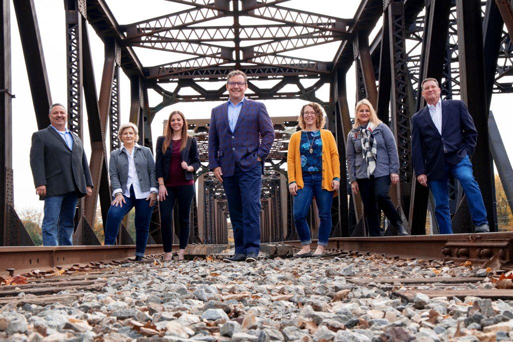 A group of people standing on train tracks in front of a bridge.