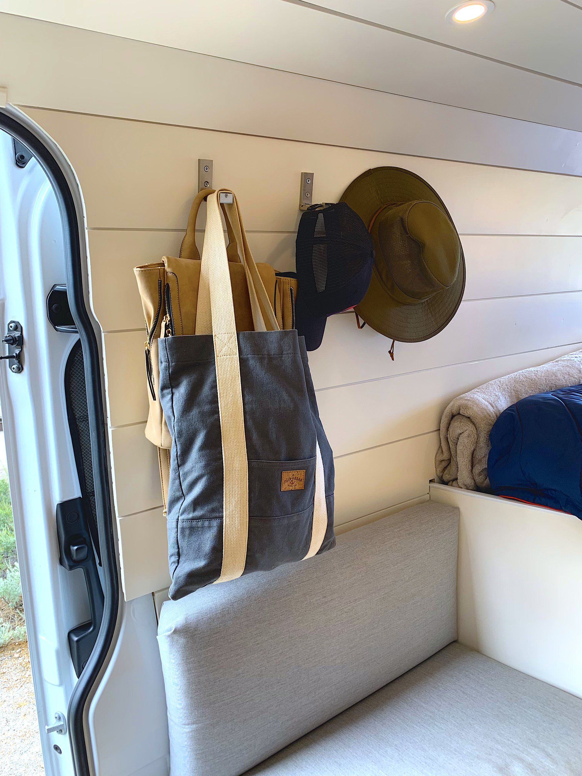 a bag and a hat are hanging on a wall in a van