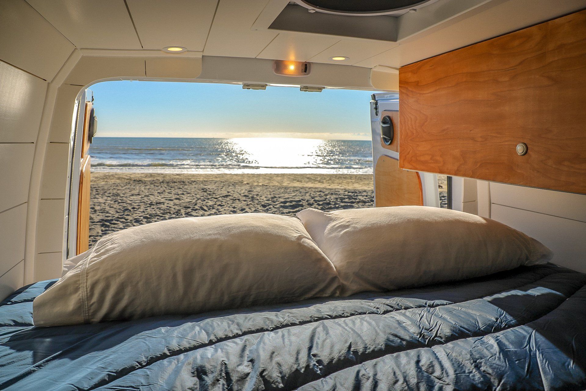 a bed in a van with a view of the ocean .