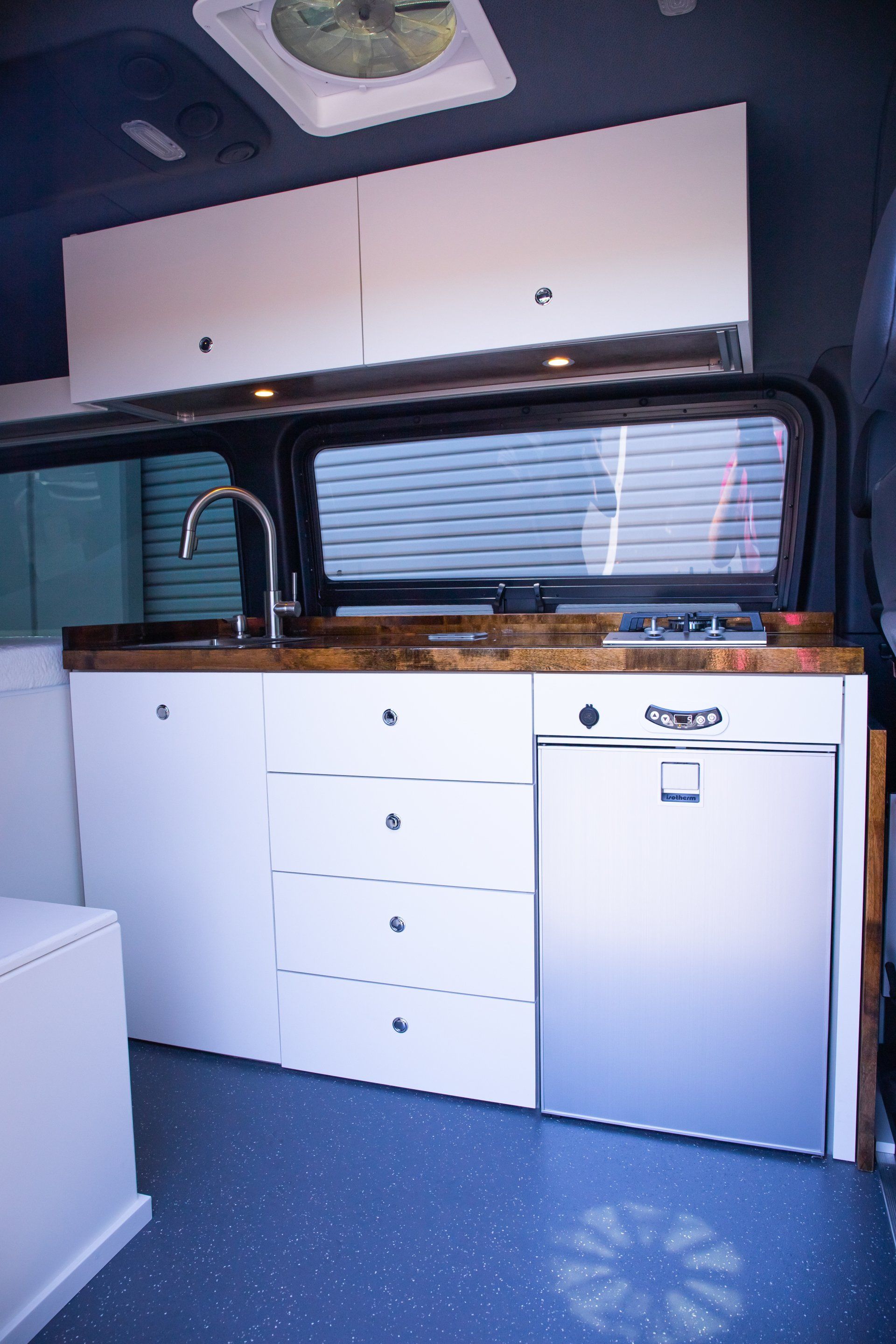a kitchen in a van with white cabinets and a stainless steel dishwasher