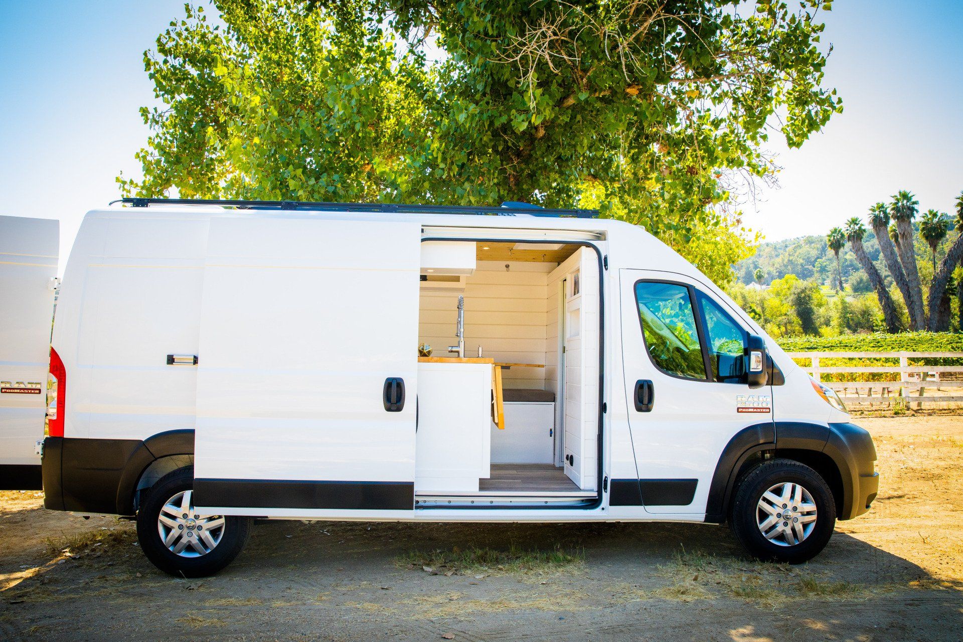 a white van is parked in a field with its doors open .