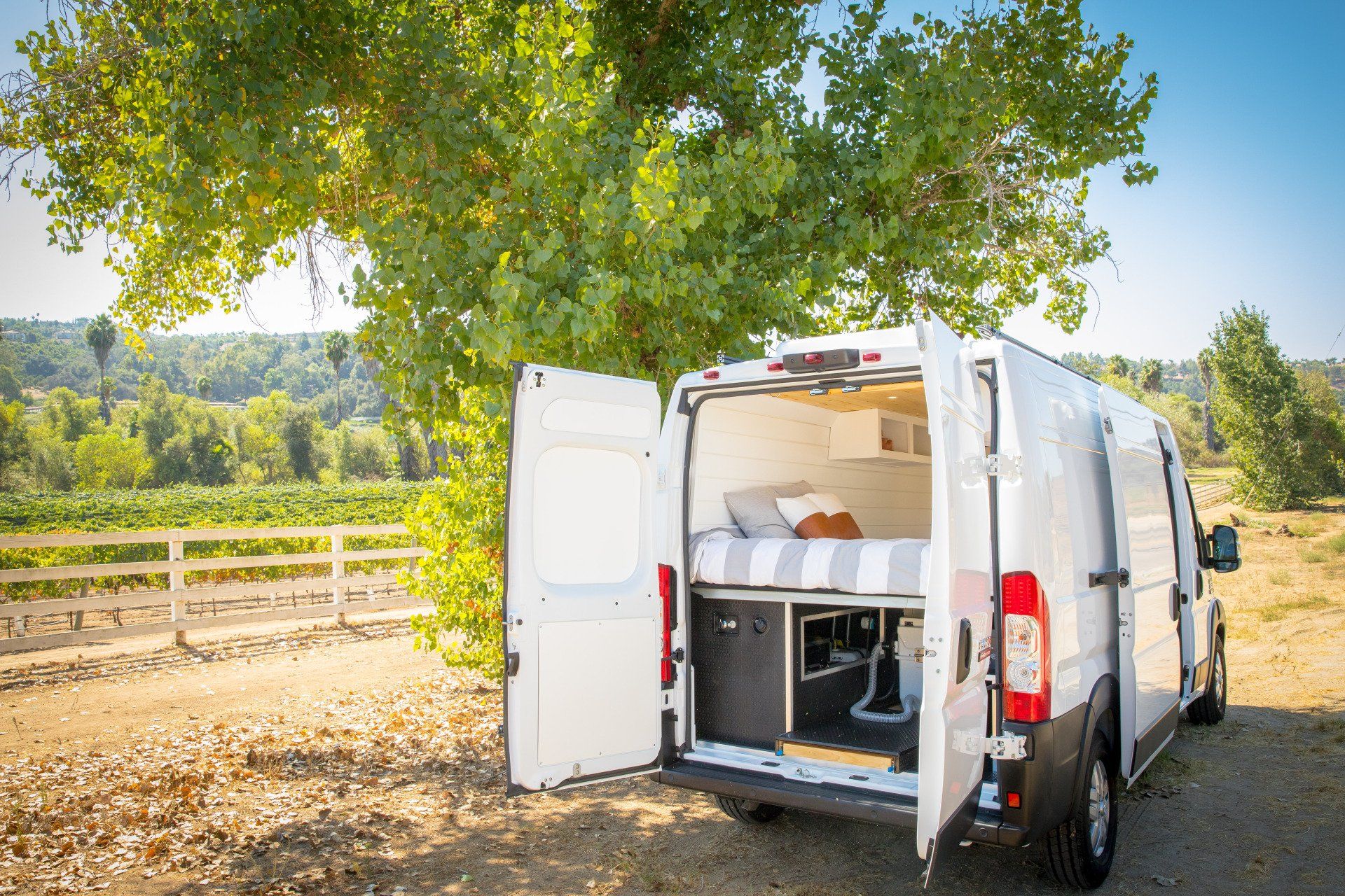 a white van is parked in a field with its doors open .