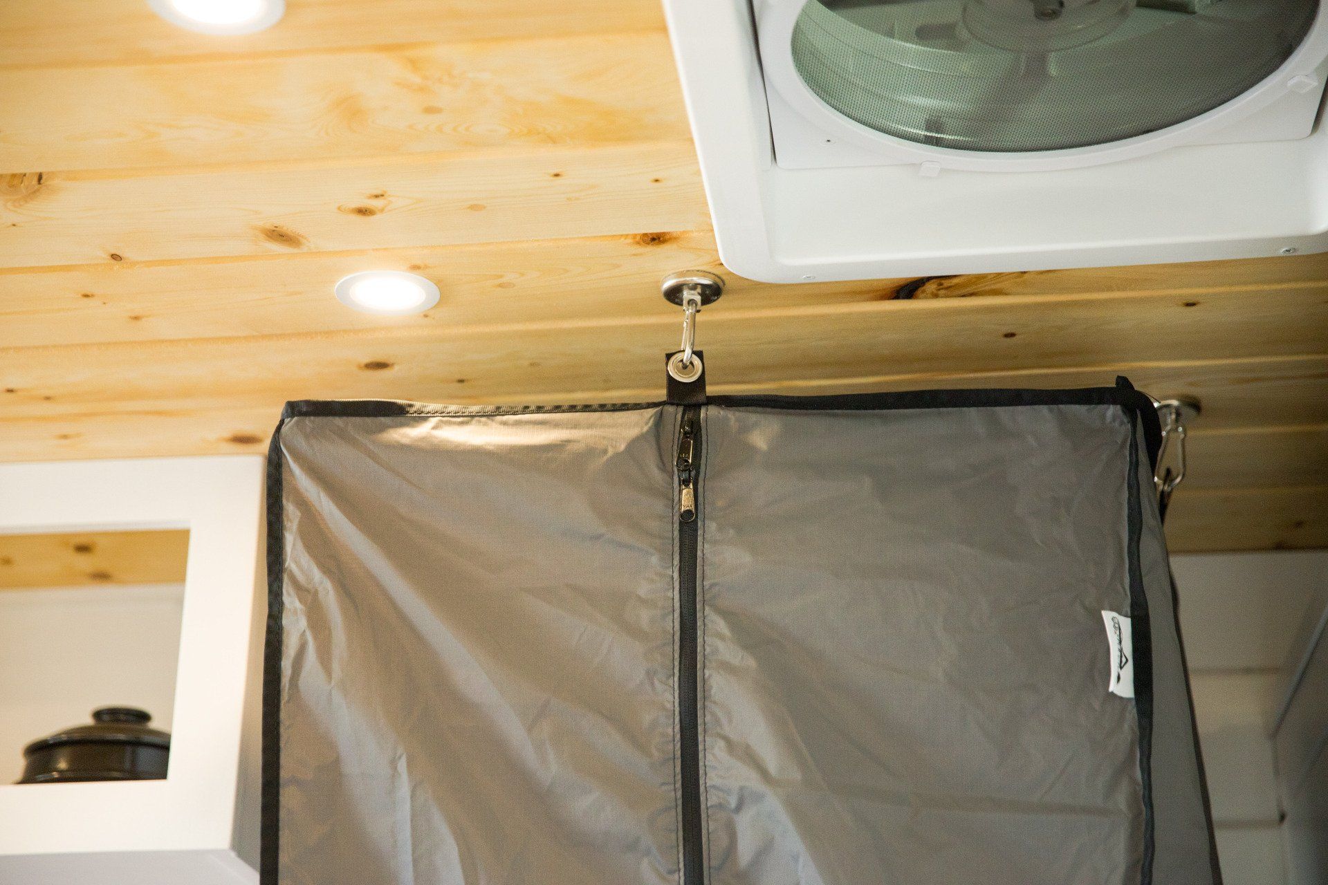 a fan is hanging from the ceiling next to a bag hanging from the ceiling .
