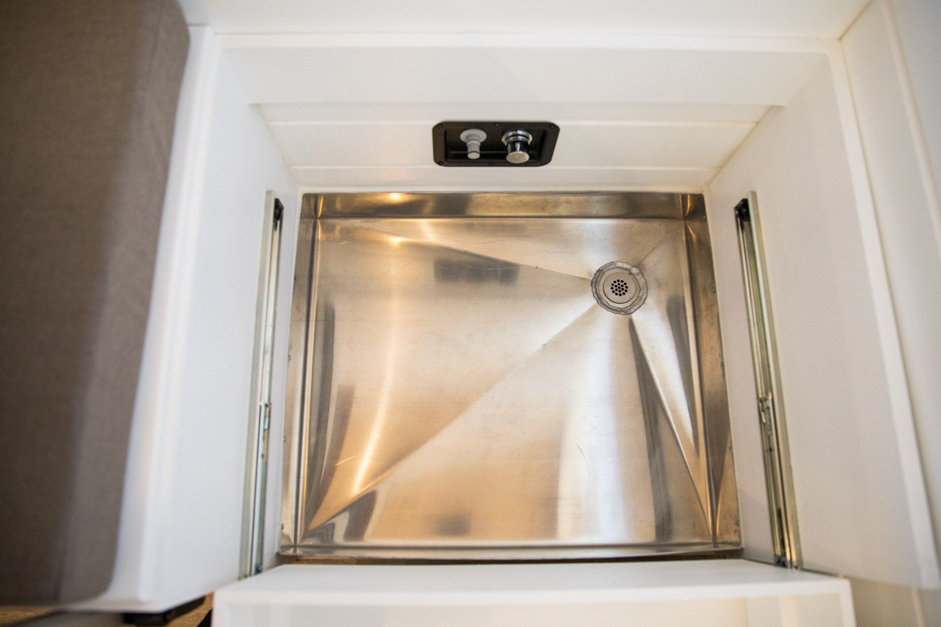 a stainless steel sink in a bathroom with a drain