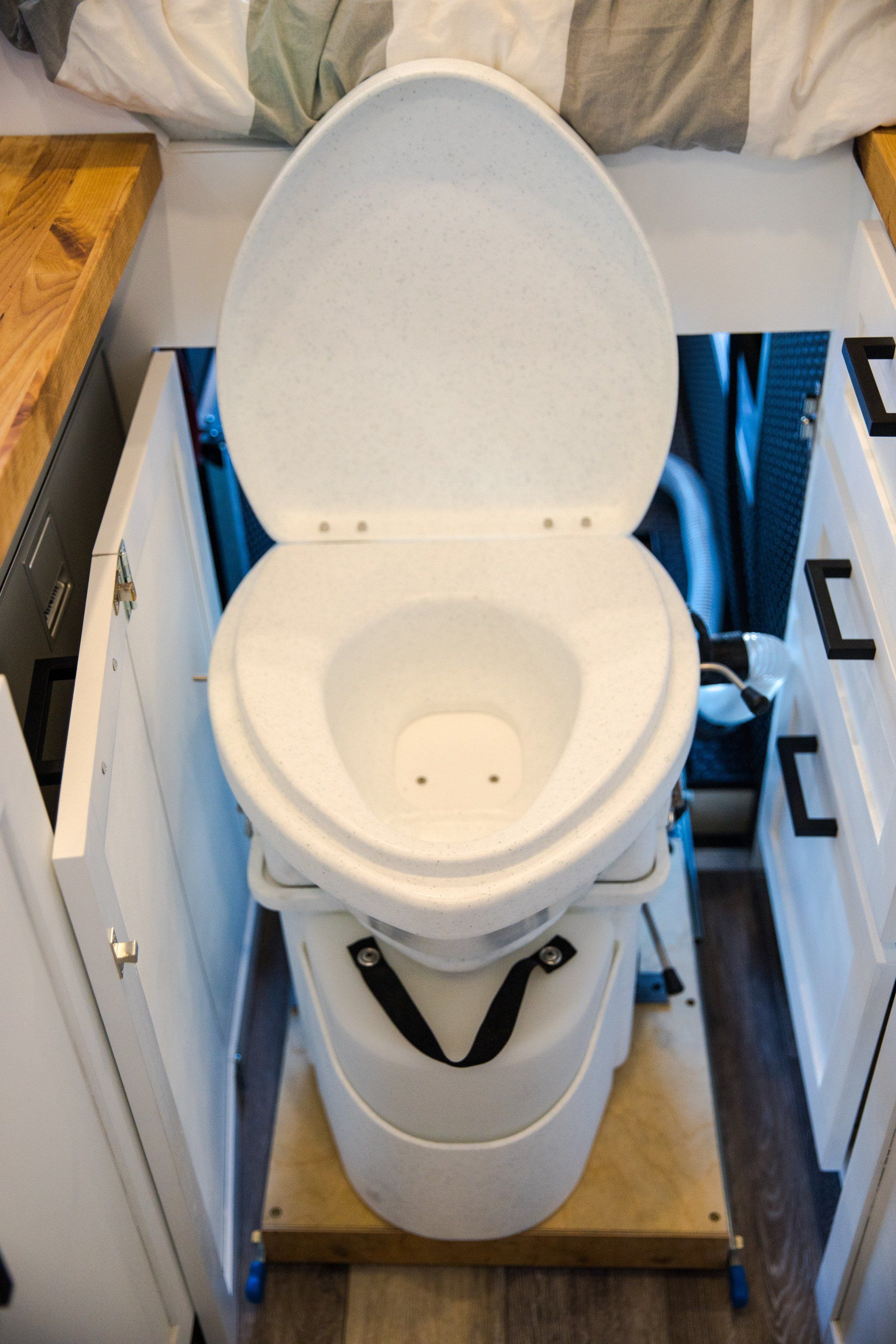 a toilet is sitting under a bed with the lid open