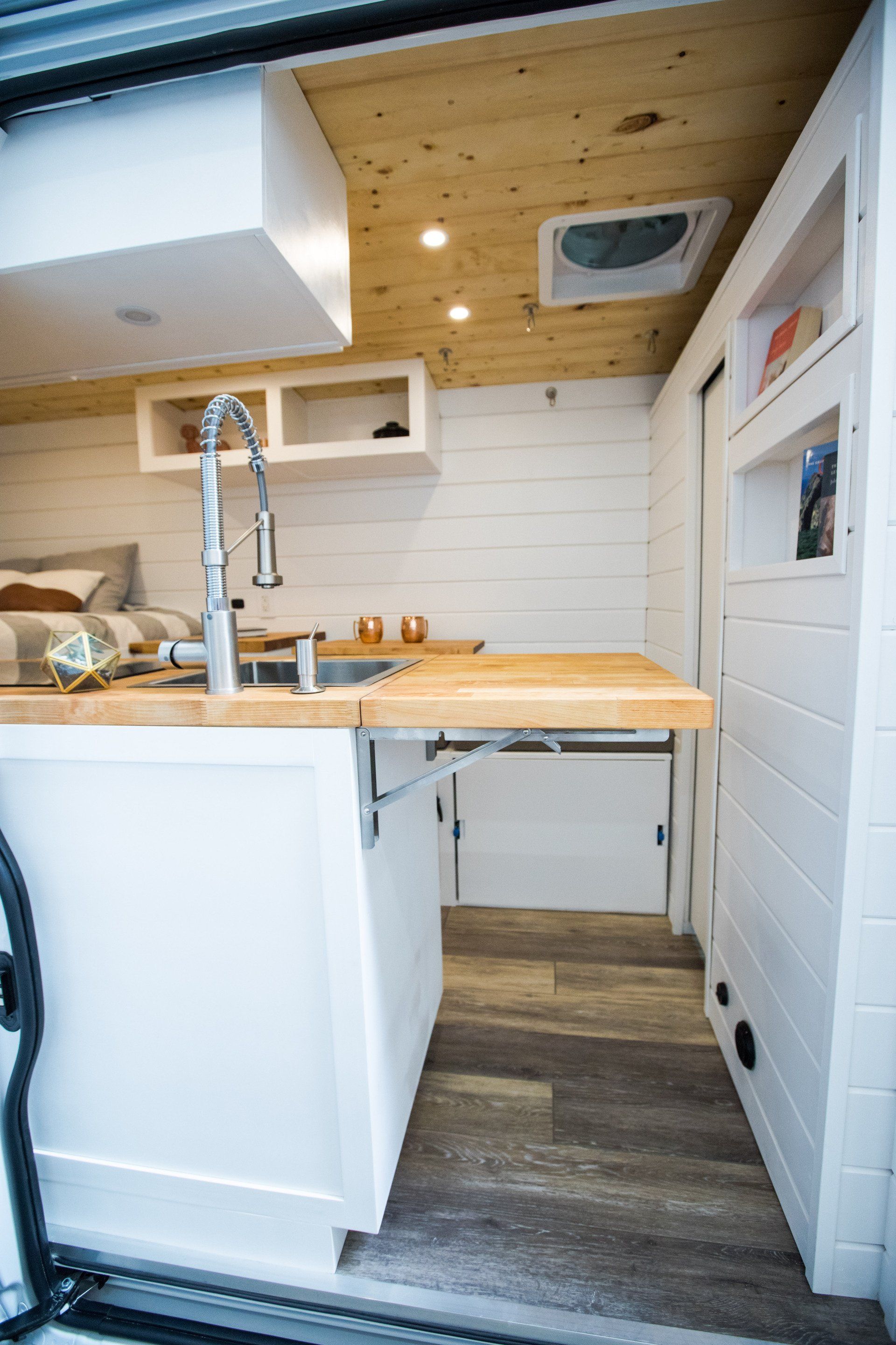 a kitchen in a van with a sink and a wooden counter top .