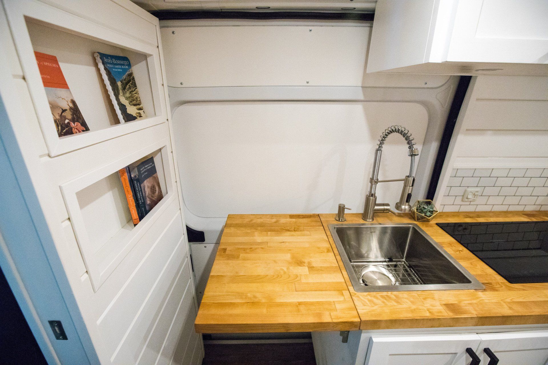 a kitchen with a sink , stove , and wooden counter top .