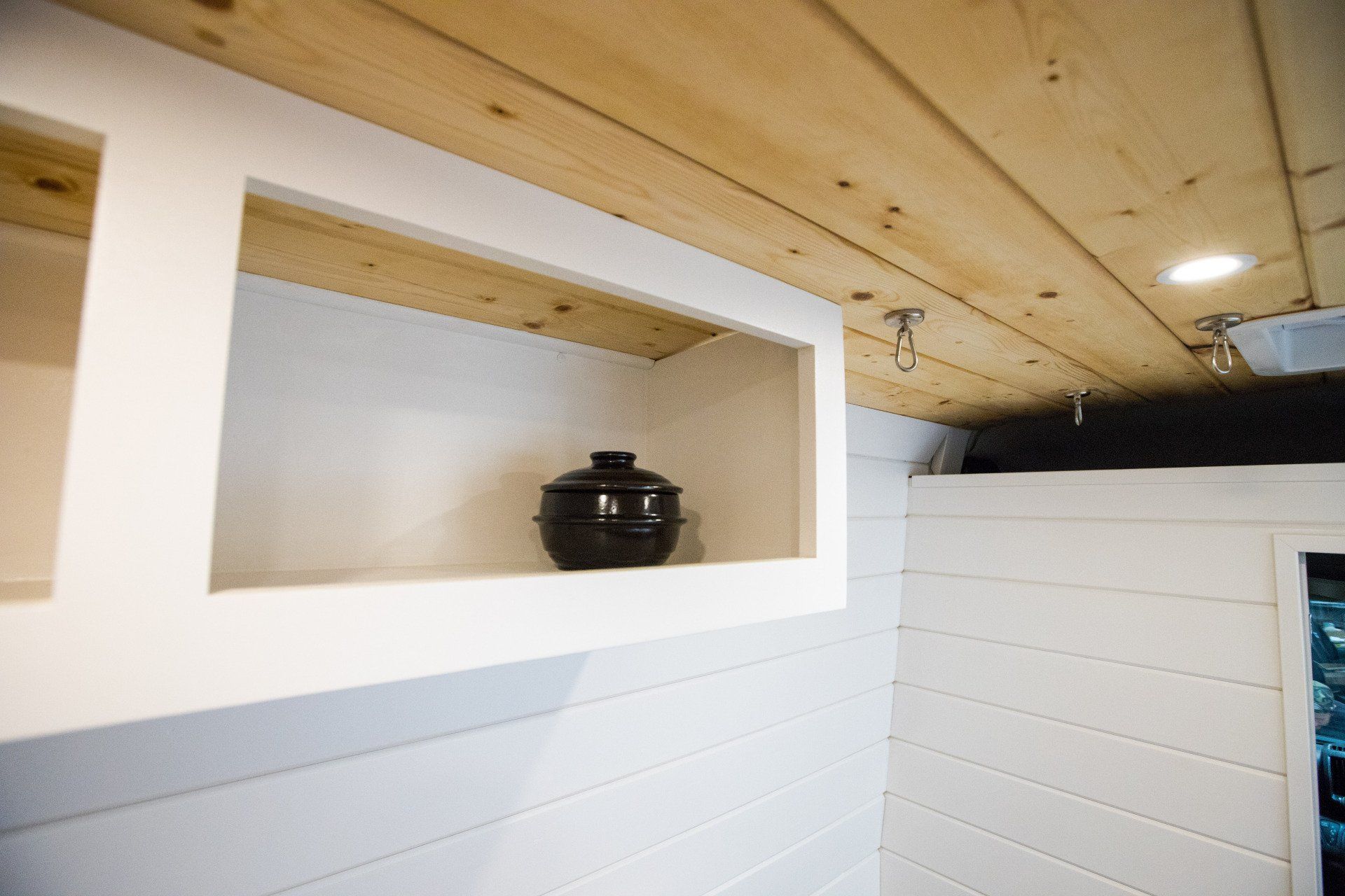 a pot is sitting on a shelf in a room with a wooden ceiling .