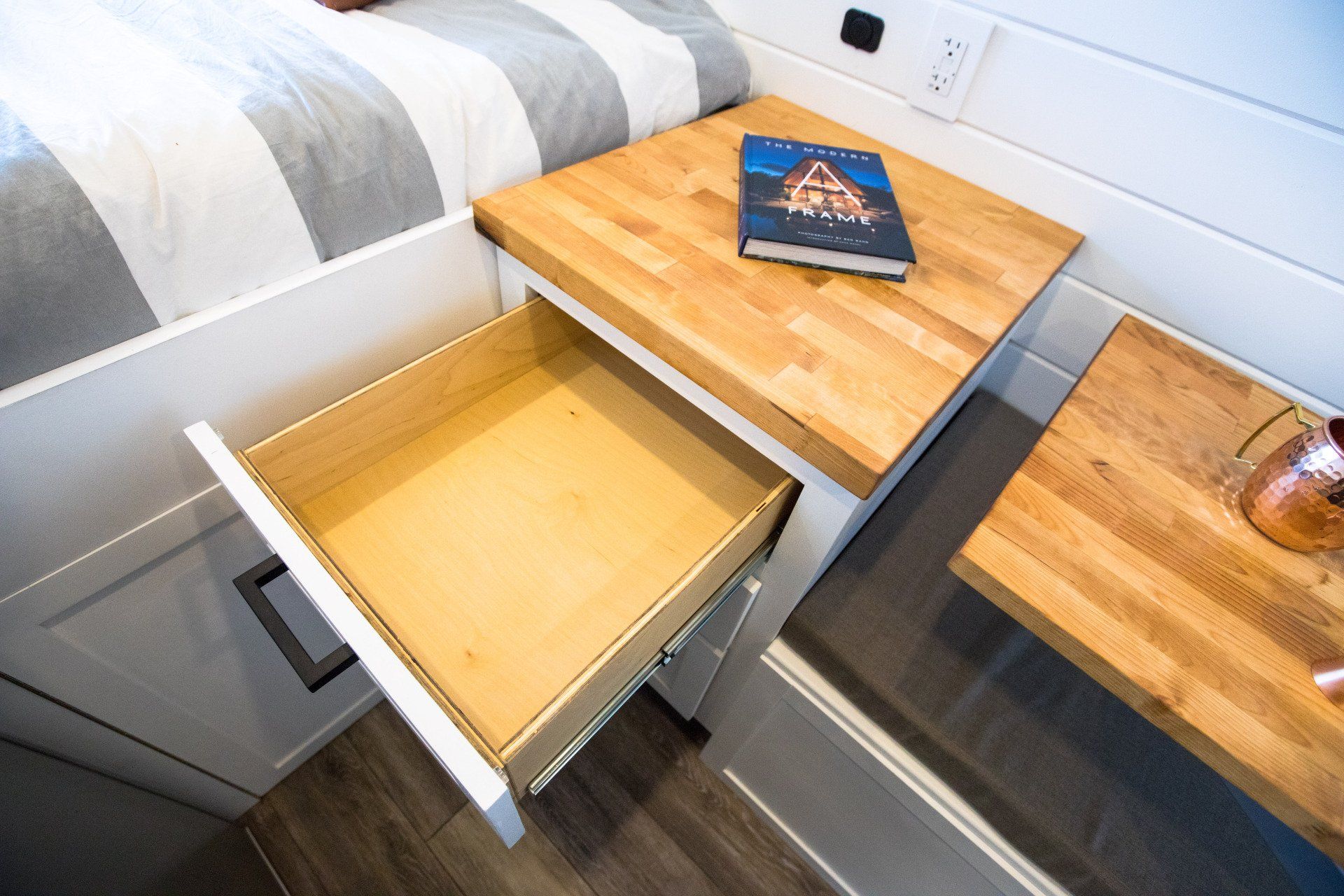 a wooden nightstand with a drawer open next to a bed .