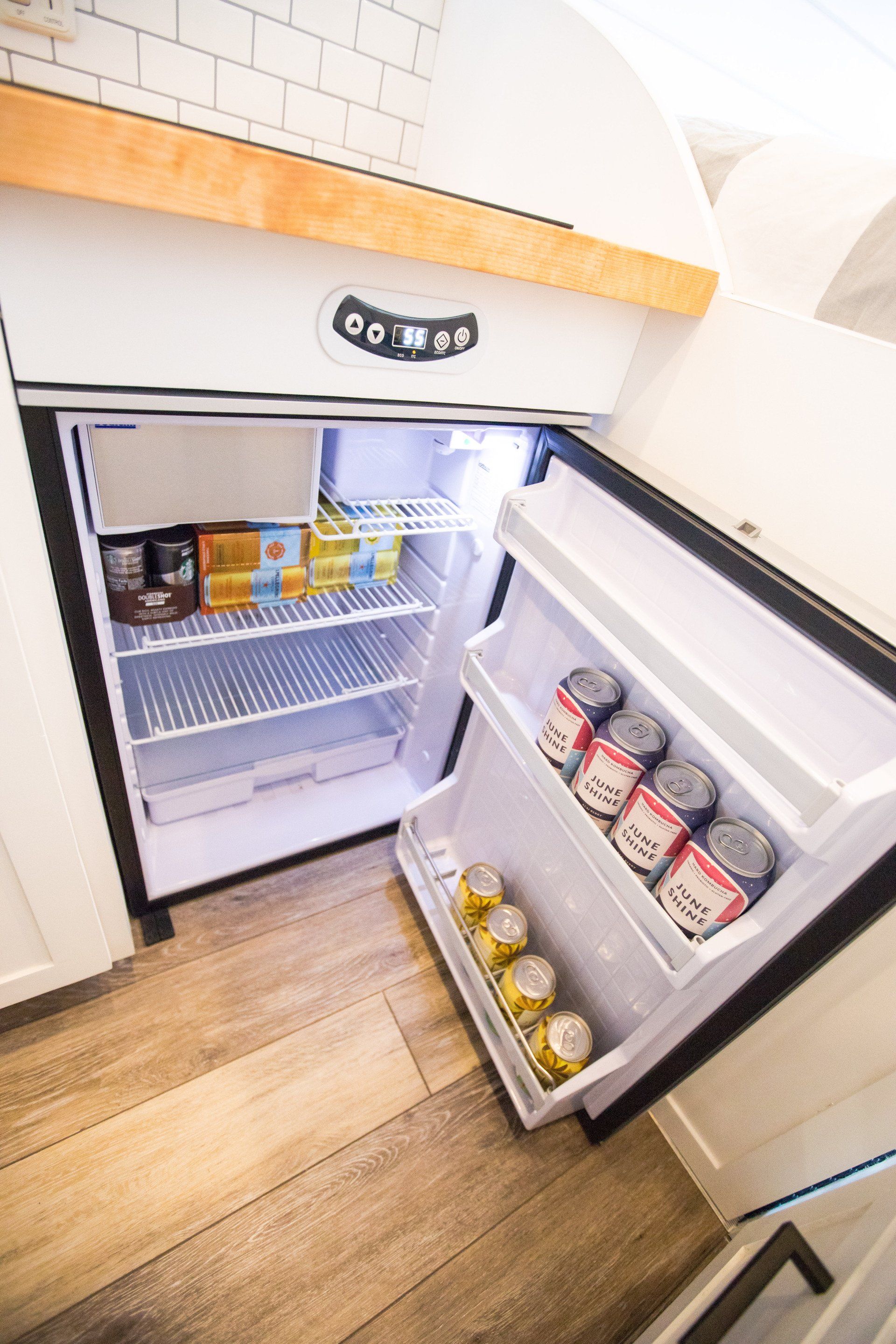a small refrigerator with the door open and a lot of food in it .