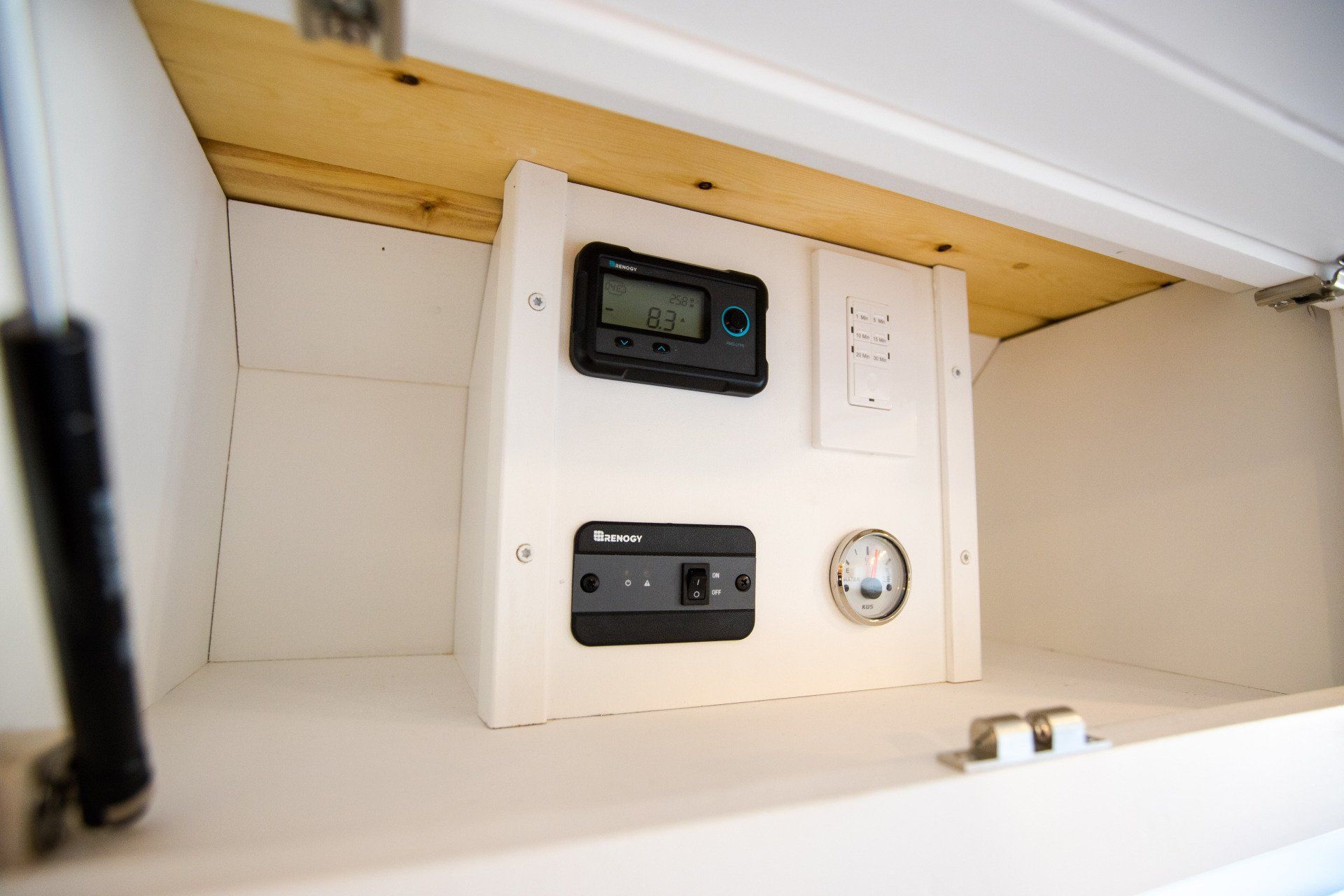 a white cabinet with a thermometer and a clock on it .