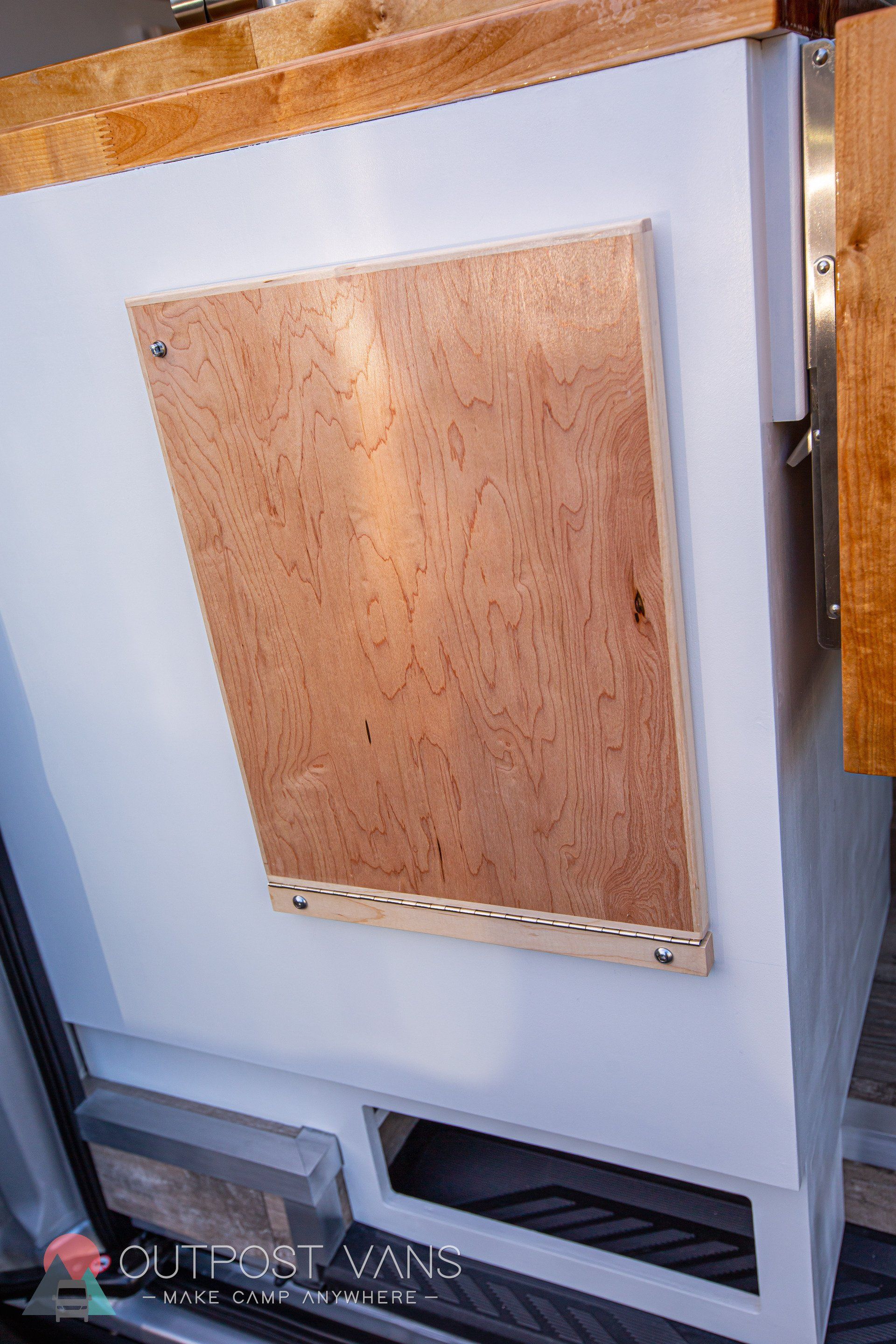 a piece of wood is sitting on top of a white cabinet .