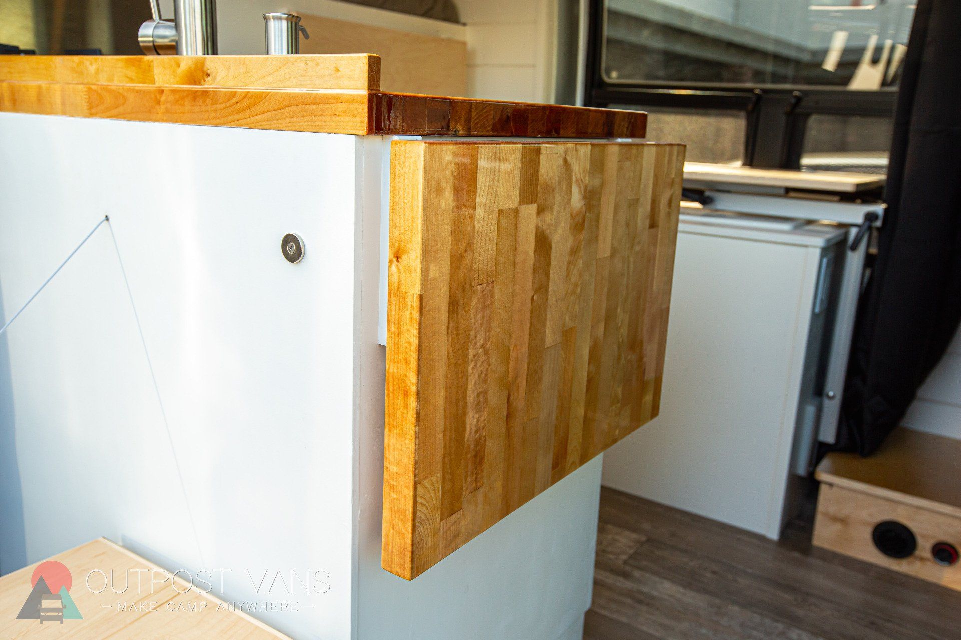 a wooden table is attached to a white wall in a kitchen .