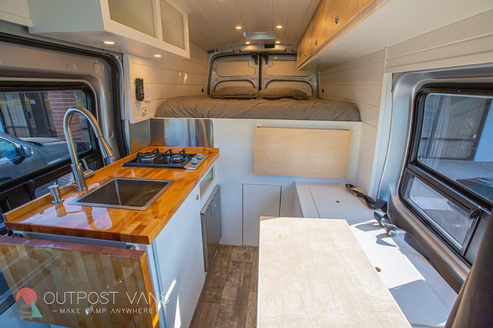 the inside of a camper van with a sink , stove , and bed .