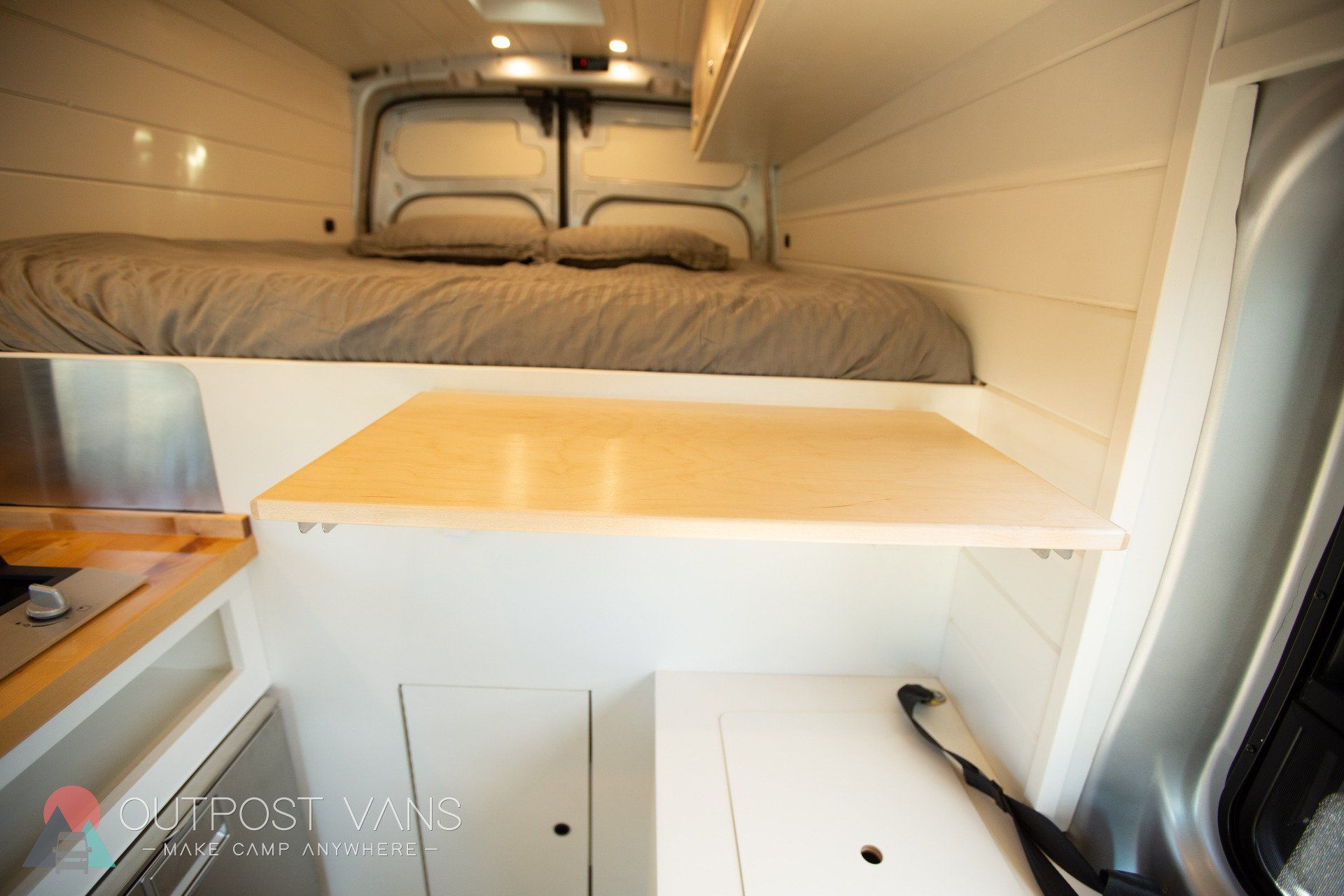 the inside of a van with a bed and a table .