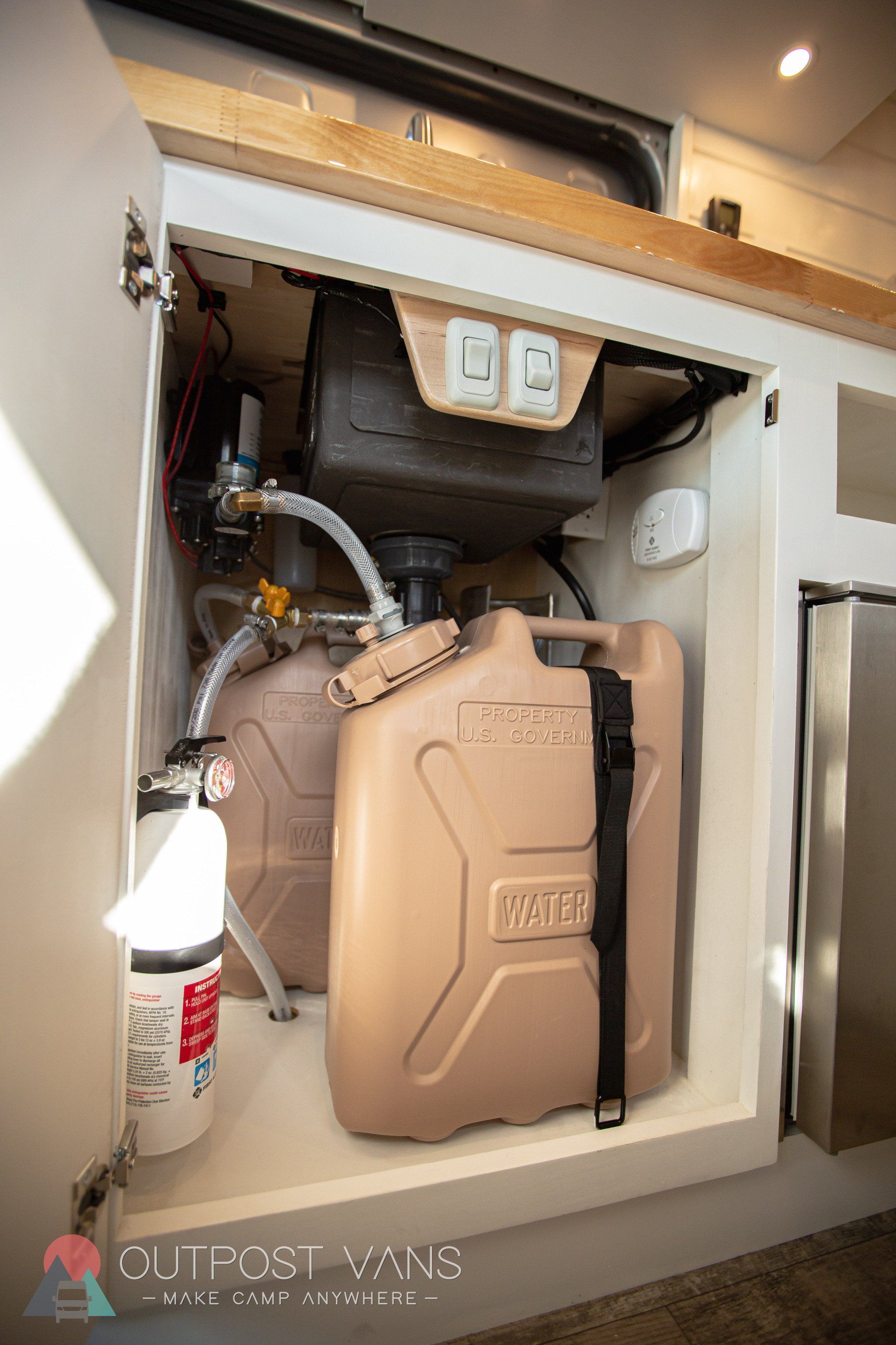 a water tank is sitting inside of a cabinet in a kitchen .
