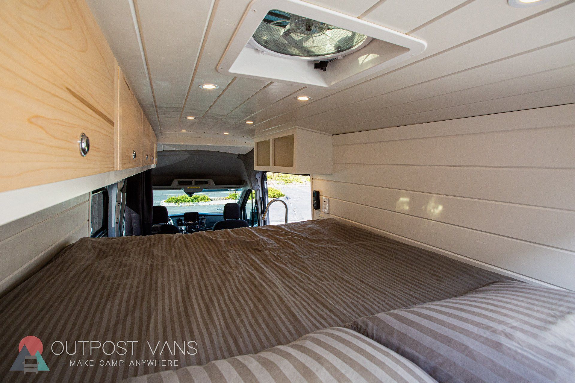 a bed in the back of a van with a fan on the ceiling .