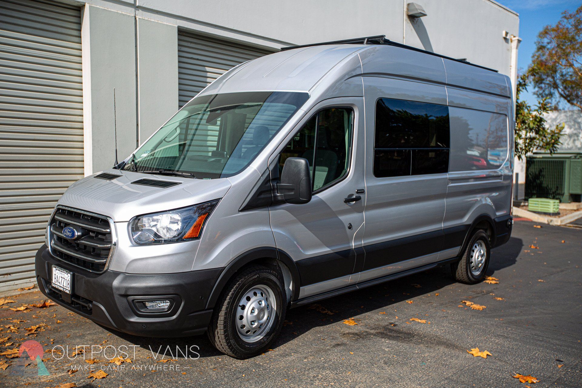 a silver van is parked in front of a building .