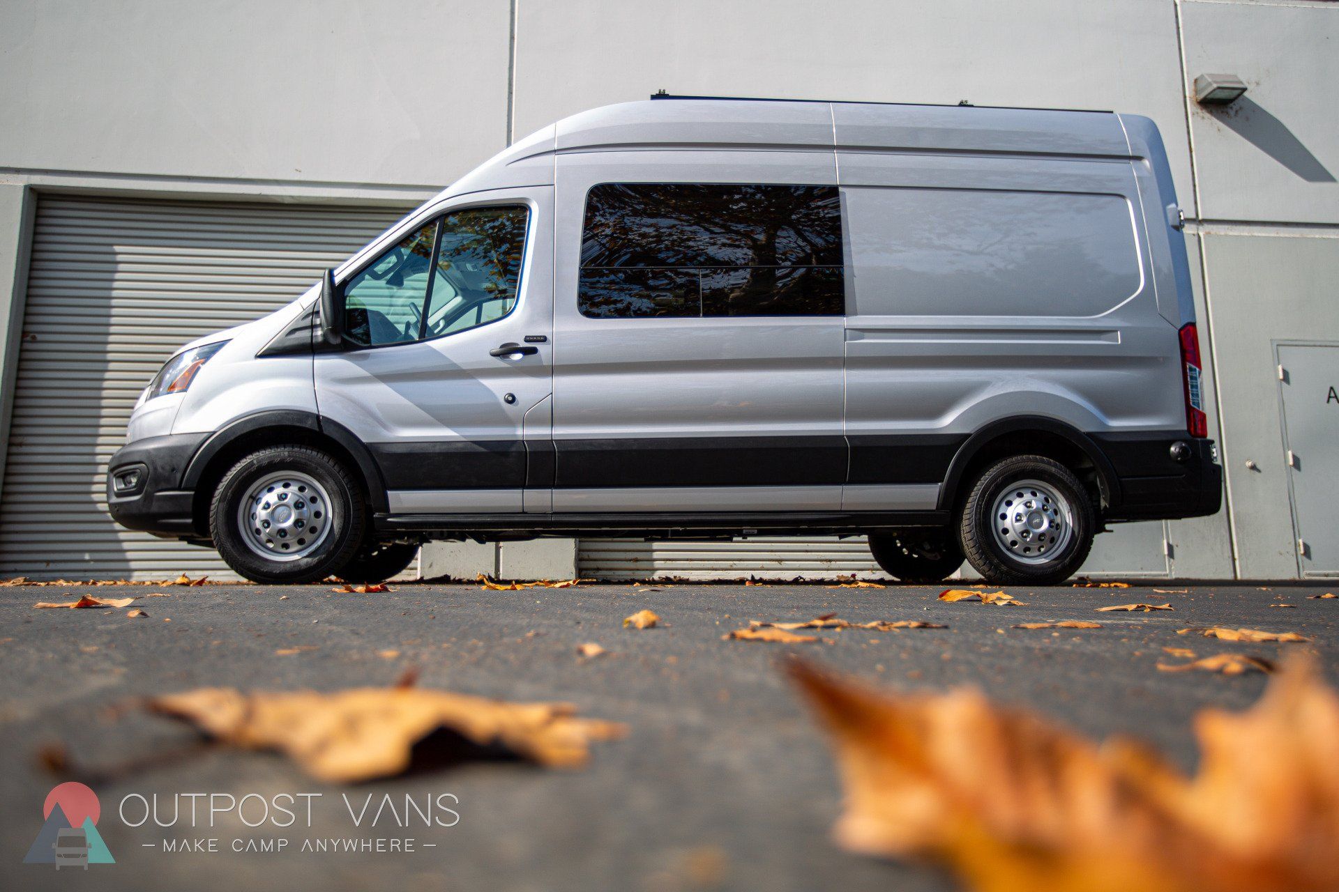 a silver van is parked in front of a building .