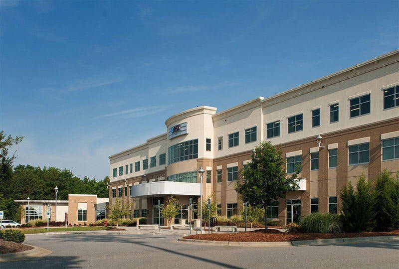 Exterior view of a three-story beige and tan office building under a blue sky.