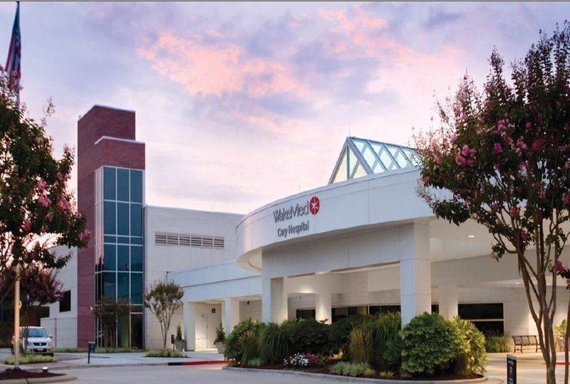Exterior view of the Walker Baptist Medical Center with a red brick tower and entrance under a bright sky.