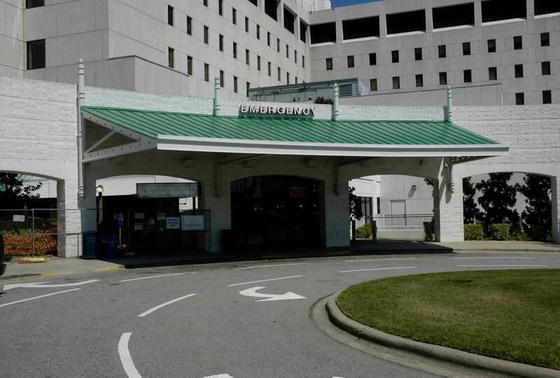 Entrance to a hospital building with a green roof and a white exterior.