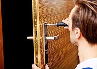 Young man fixing the door — Safes & Vaults-Opening & Repairing in Pennsauken, NJ Young man fixing the door — Safes & Vaults-Opening & Repairing in Pennsauken, NJ