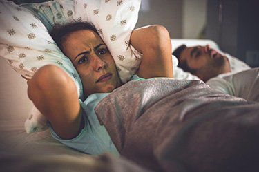 Picture of Woman covering her ears with pillow