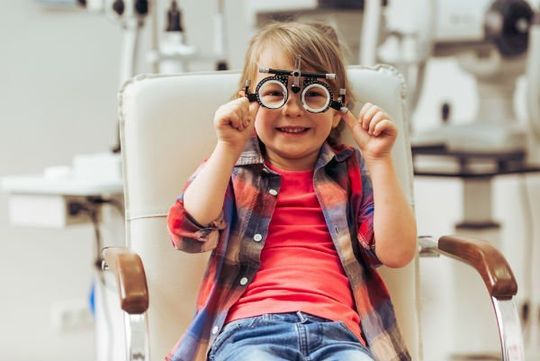 una bimba sorridente che fa una visita oculistica