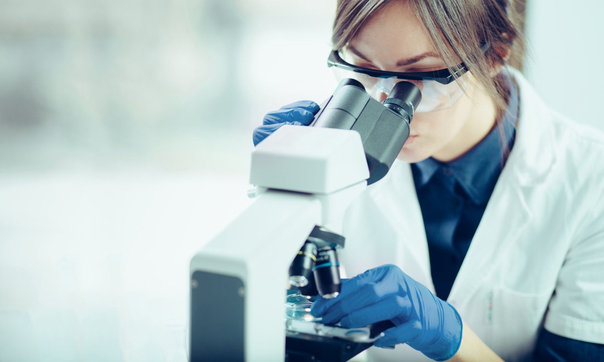 Young scientist looking through a microscope in a laboratory. Young scientist doing some research.