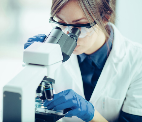 Young scientist looking through a microscope in a laboratory. Young scientist doing some research.