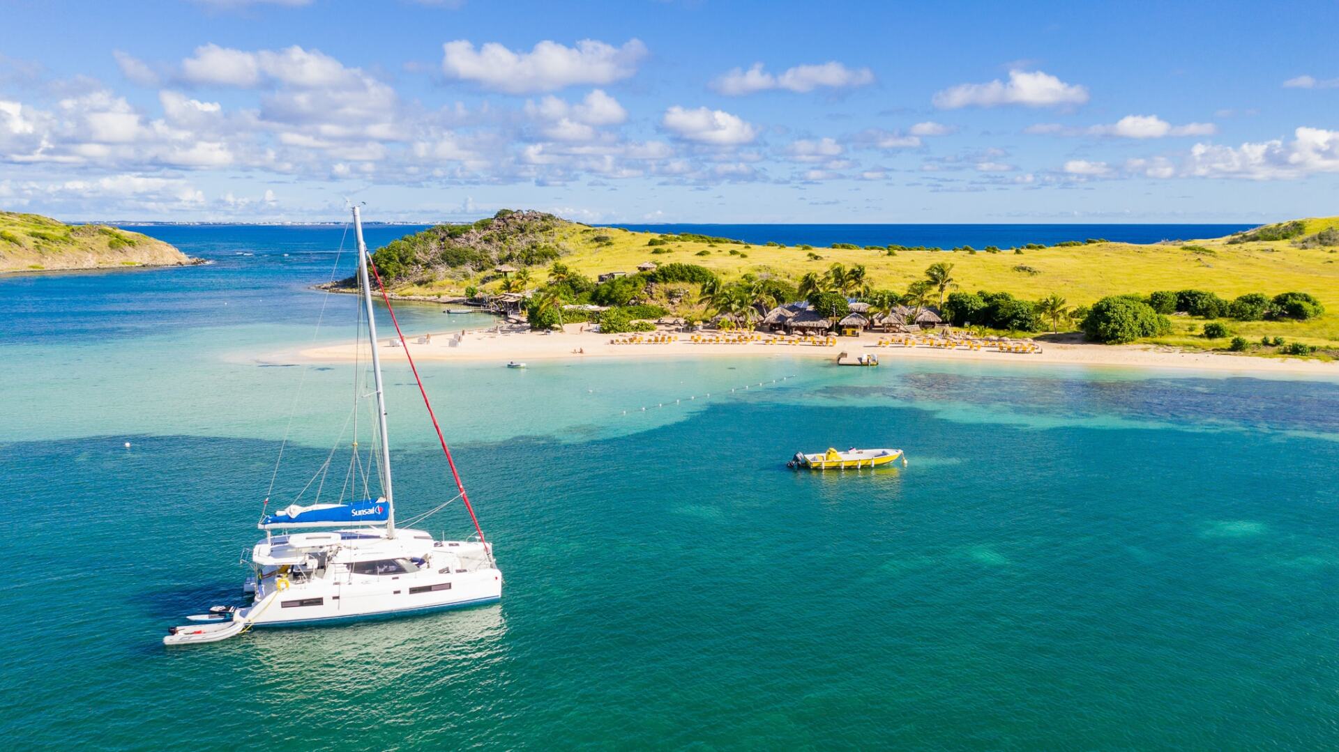 An aerial view of a sailboat in the ocean near a small island.