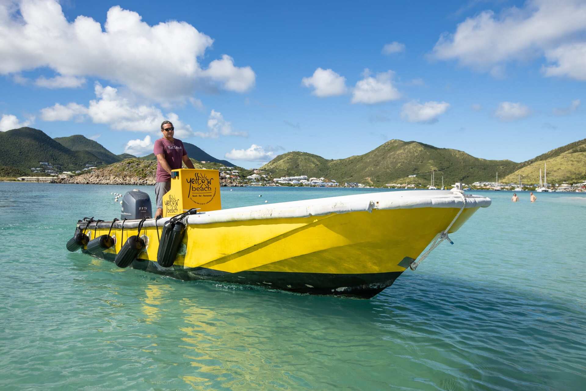 A man is driving a yellow boat in the ocean.