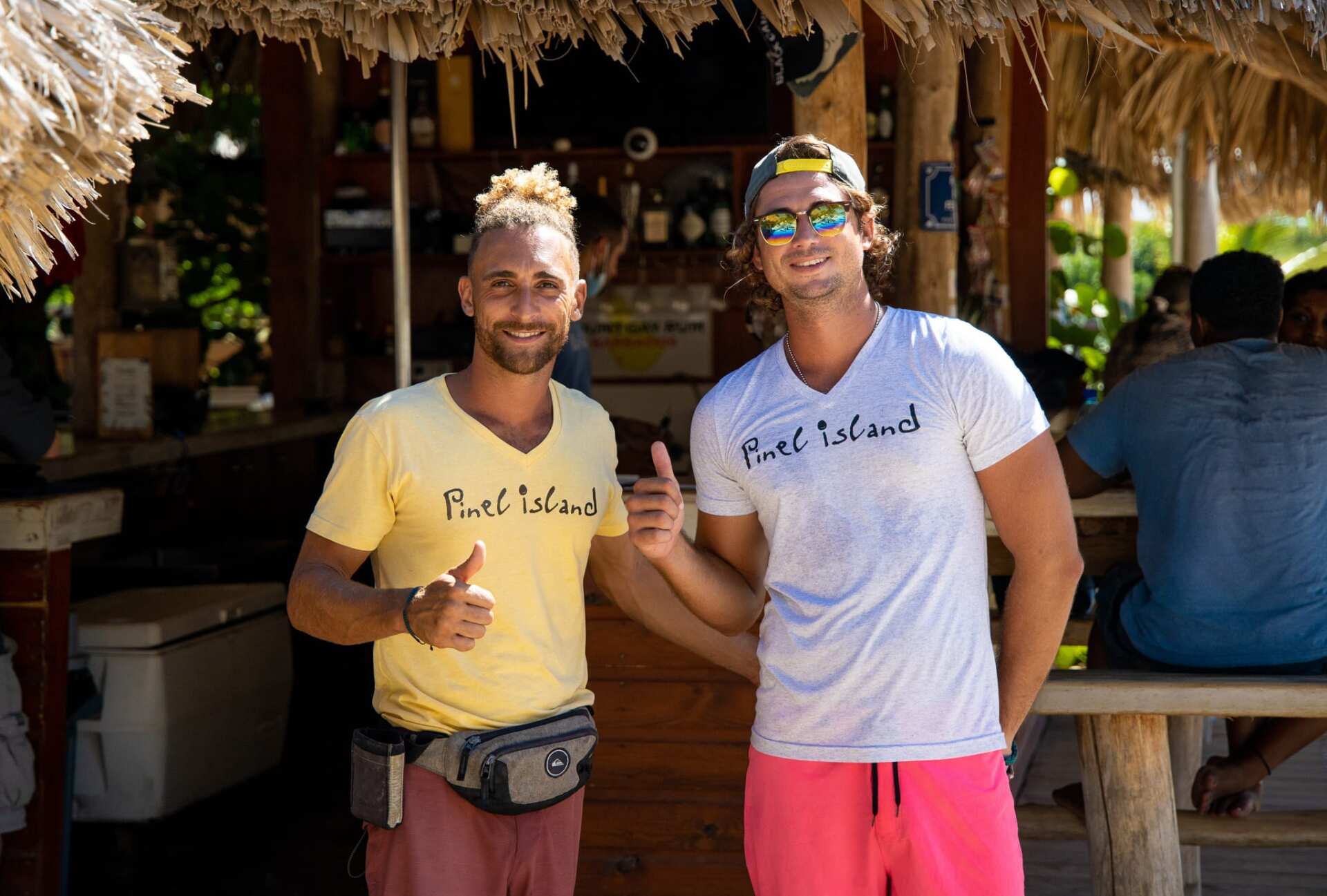 Two men are standing next to each other and giving a thumbs up.