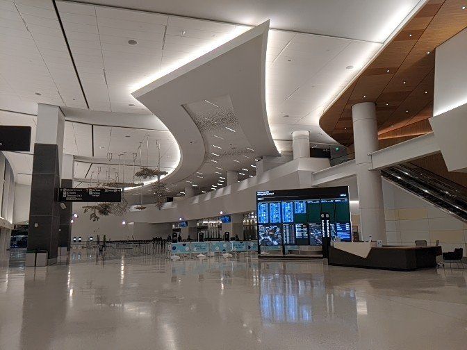 One of the throughways at Harvey Milk terminal, showing a ceiling light fixture over the main walkways and wayfinding signage in the background.