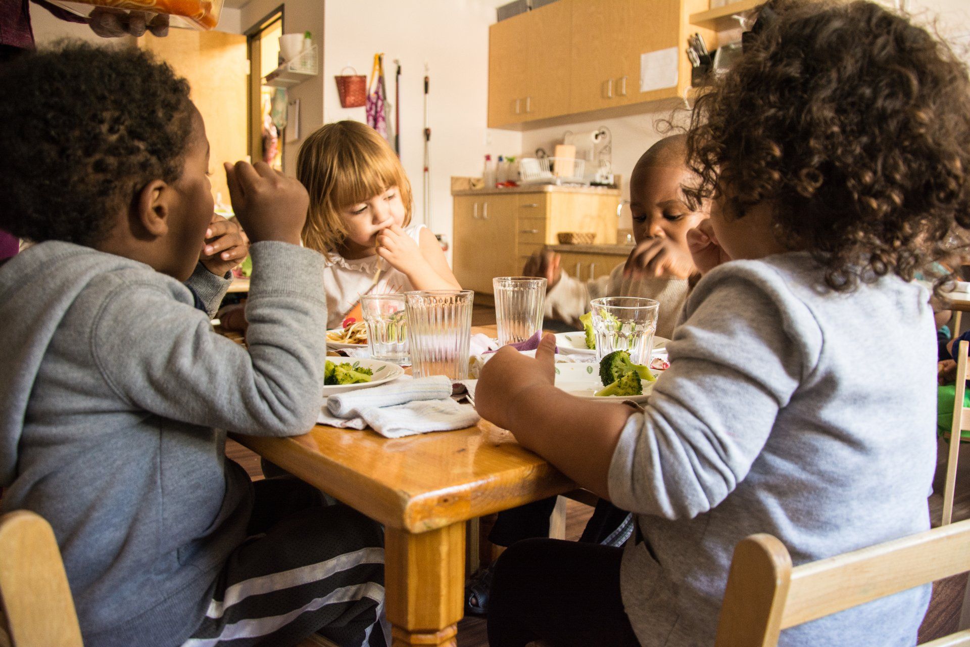 A group of children are sitting at a table eating food.