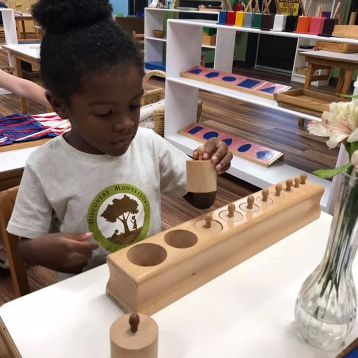 A little girl is playing with a working with montessori wooden materials