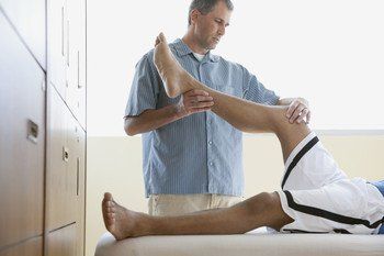 A physiotherapist working on a male patient with a sports injury
