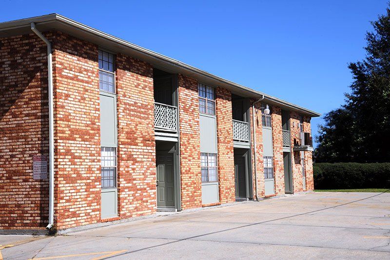 A brick apartment building with a parking lot in front of it