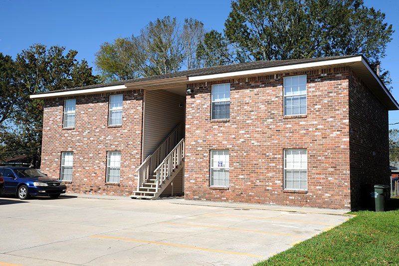 A blue car is parked in front of a brick apartment building