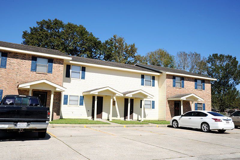 A white car is parked in front of a brick apartment building