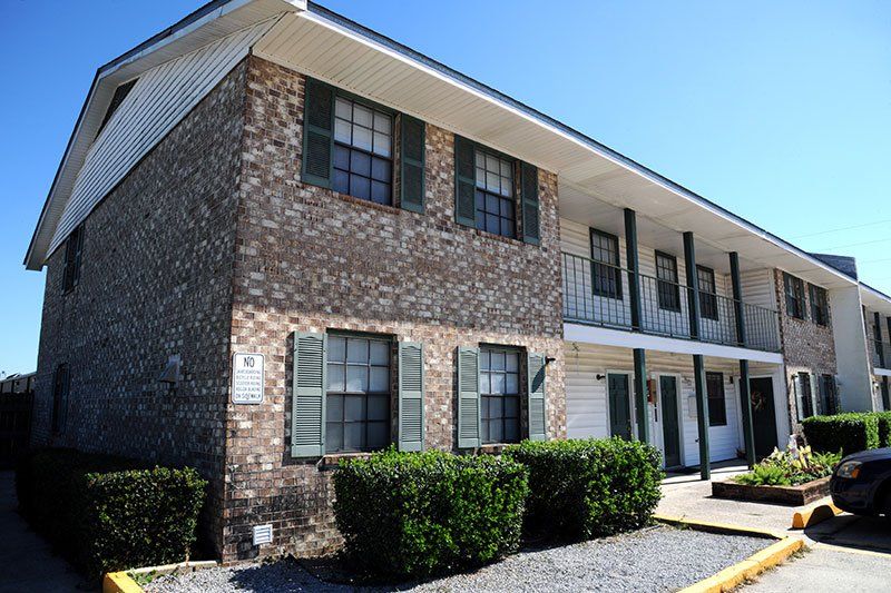 A brick apartment building with green shutters on the windows