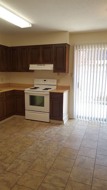 An empty kitchen with a stove and a sliding glass door.