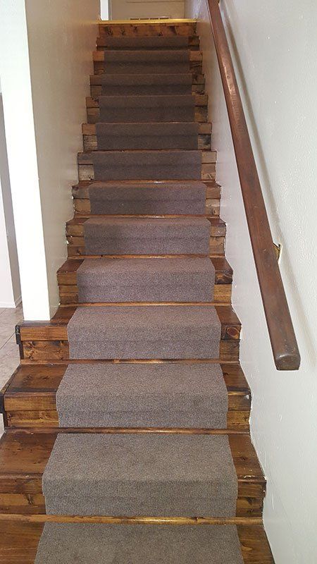 A staircase with a wooden railing and a carpeted staircase.